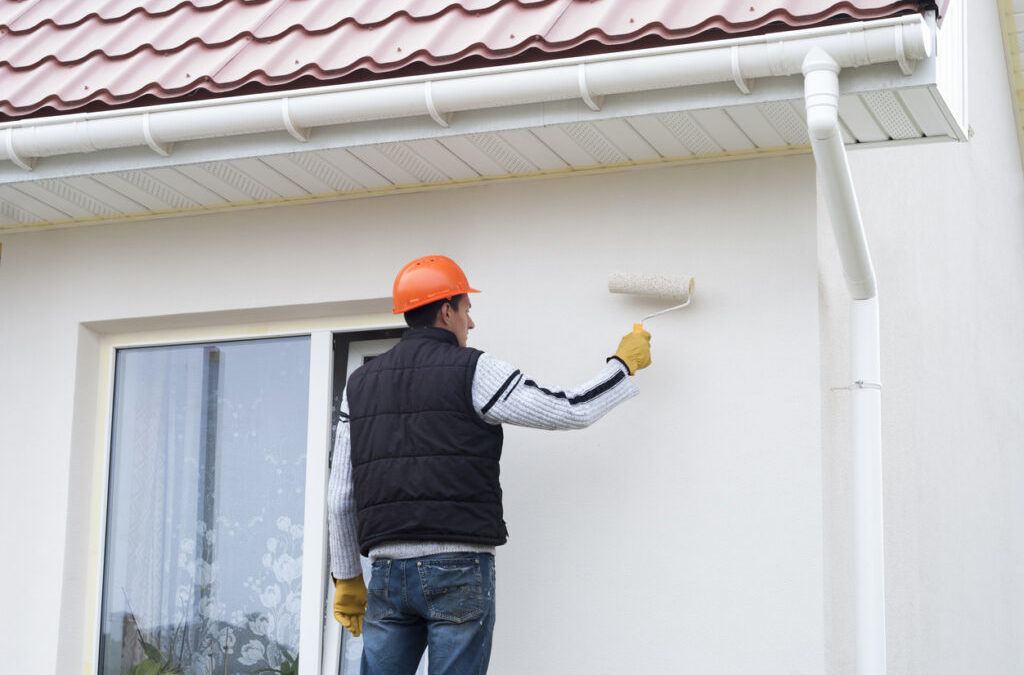 Homme équipé qui peint la façade de sa maison en blanc